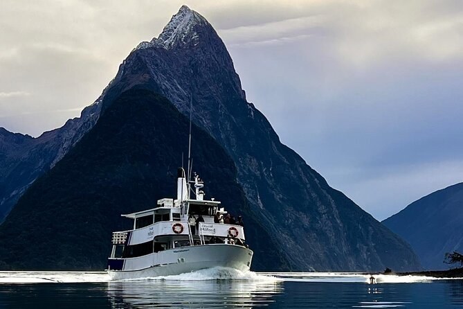 A day boat crossing the fiord under a dark pointed peak