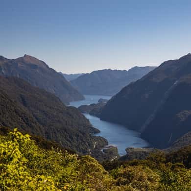 The arms of a long lake between forested ridges, seen from a hilltop