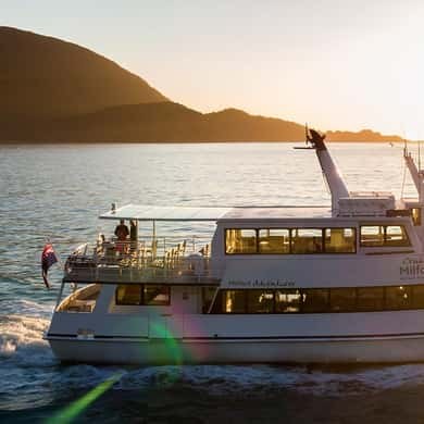 A lake cruise boat under way into a low evening sun