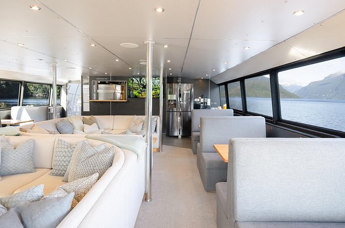 The window-lined lounge of an overnight boat, the fiord outside