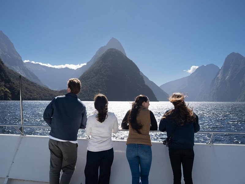 Passengers at the rail of a boat looking up the fiord towards the peaks